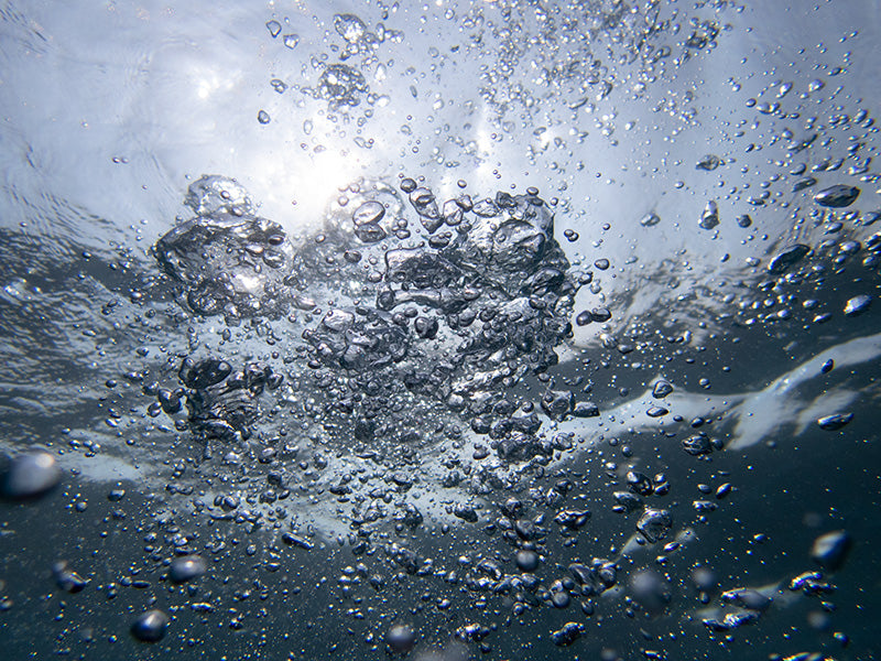 Underwater glass study composed with specular glints and aqua in silver light